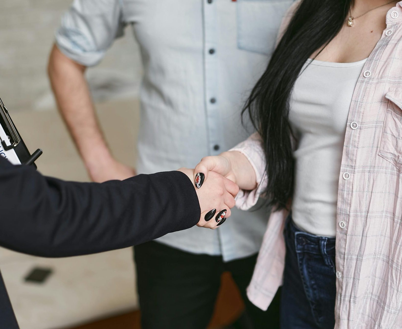 Businessperson shaking hands with a client while holding a home insurance policy document.